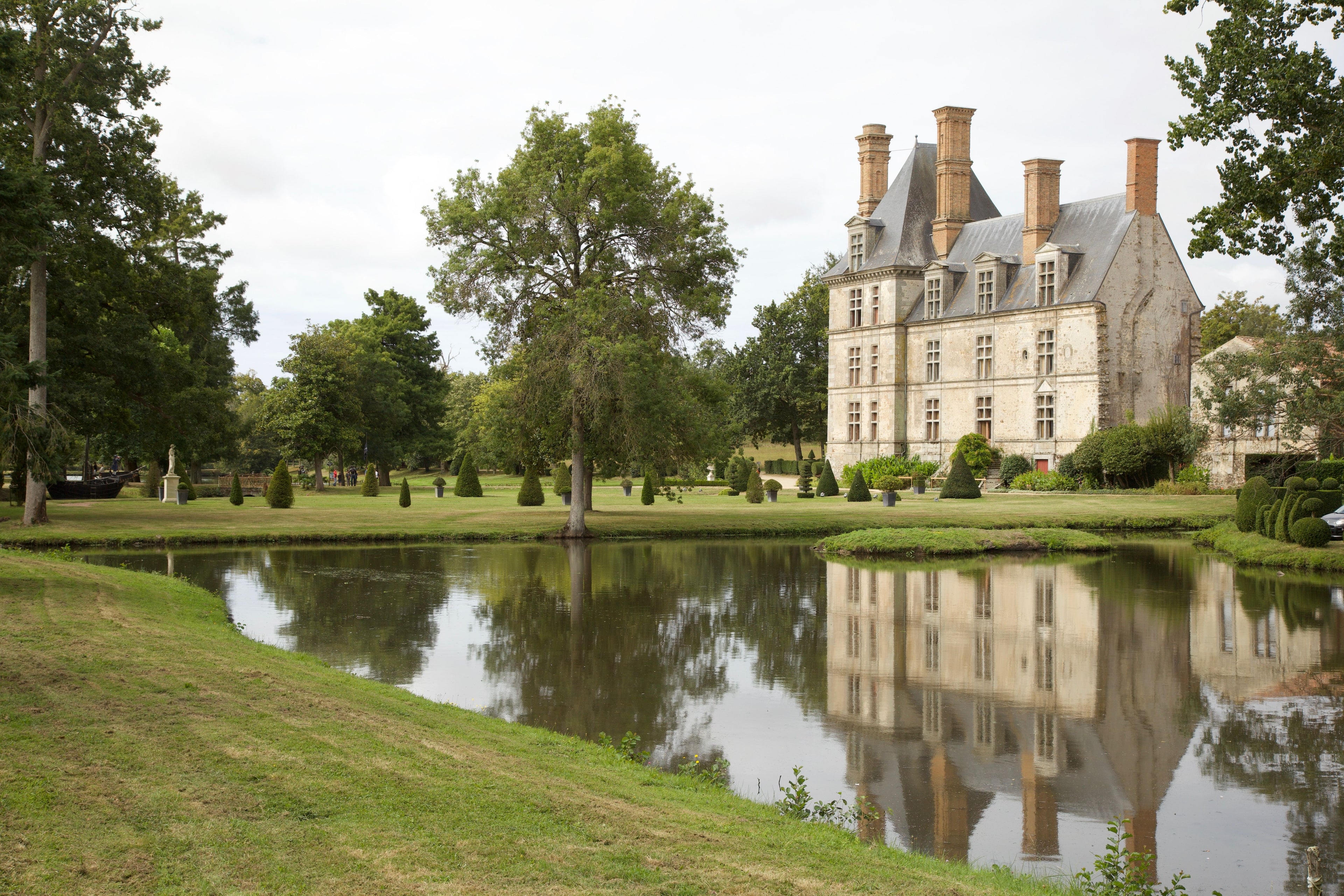 Elegant French chateau with garden and pond reflection in La Rochelle.